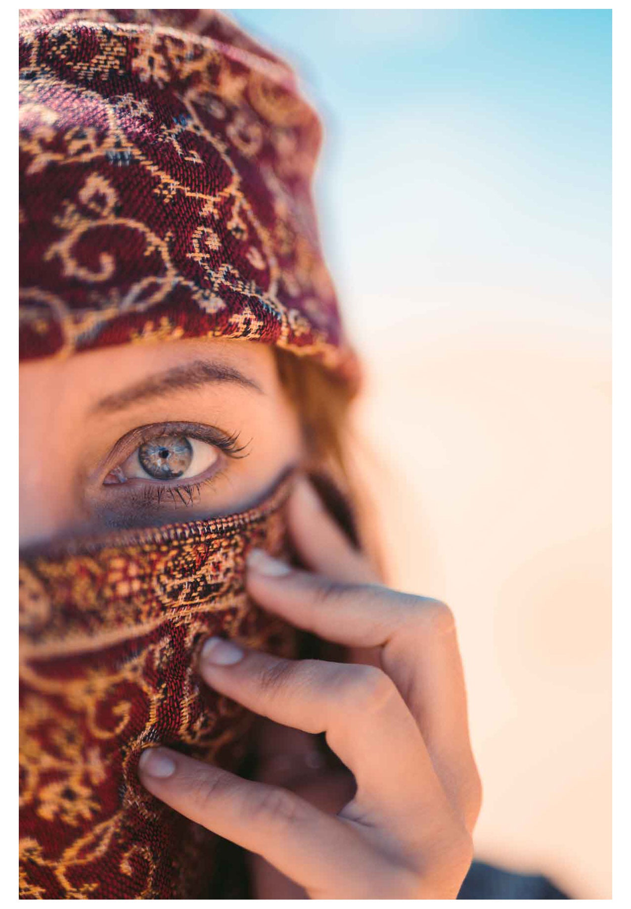 Girl with green eyes protects her skin from desert sunlight with cloth